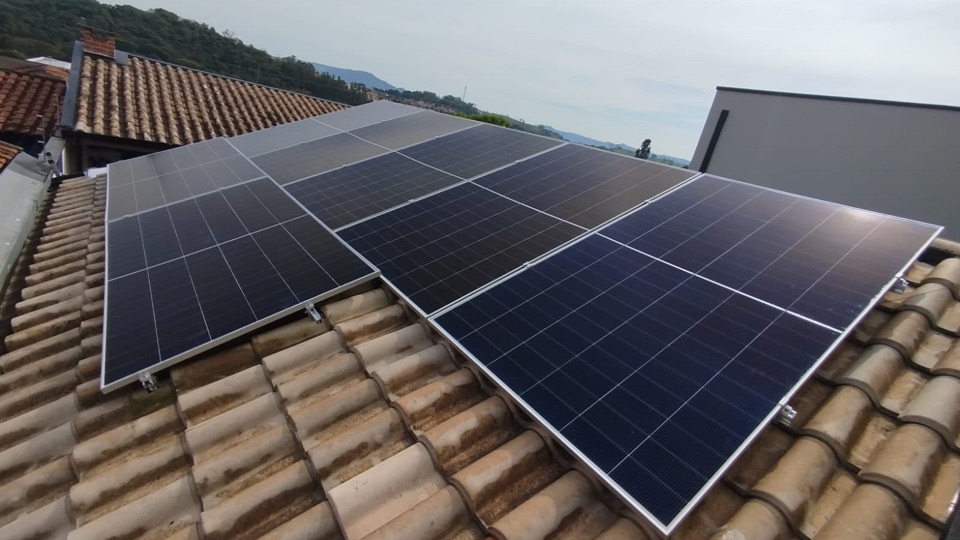 Placas solares em telhado cerâmico, com a serra ao fundo